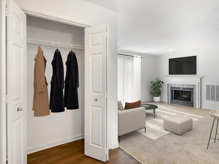 a living room with a closet with clothes hanging on the wall